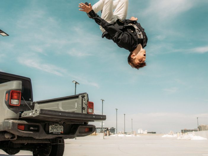 Self-confidence. Young man doing backflip off back of pickup truck.