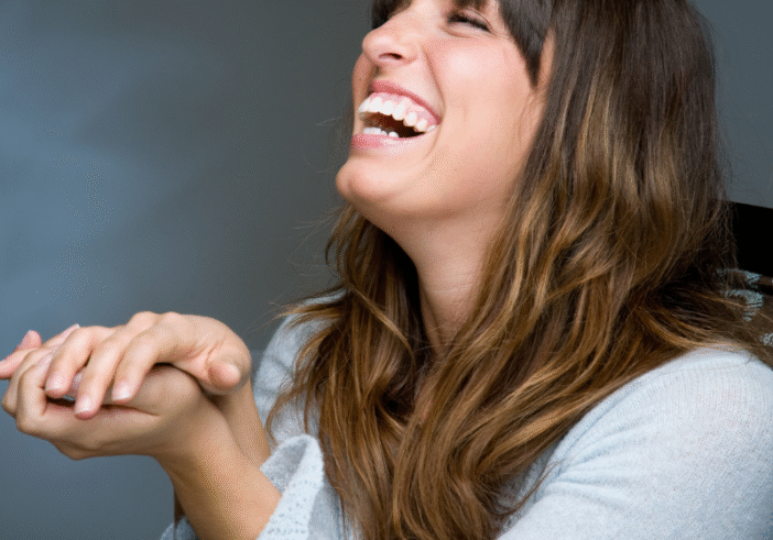 Woman laughing joyfully, symbolizing the power of laughter in releasing tension and gaining perspective.