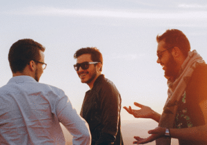 Three friends laughing and enjoying a conversation at sunset, symbolizing connection, openness, love, and understanding.